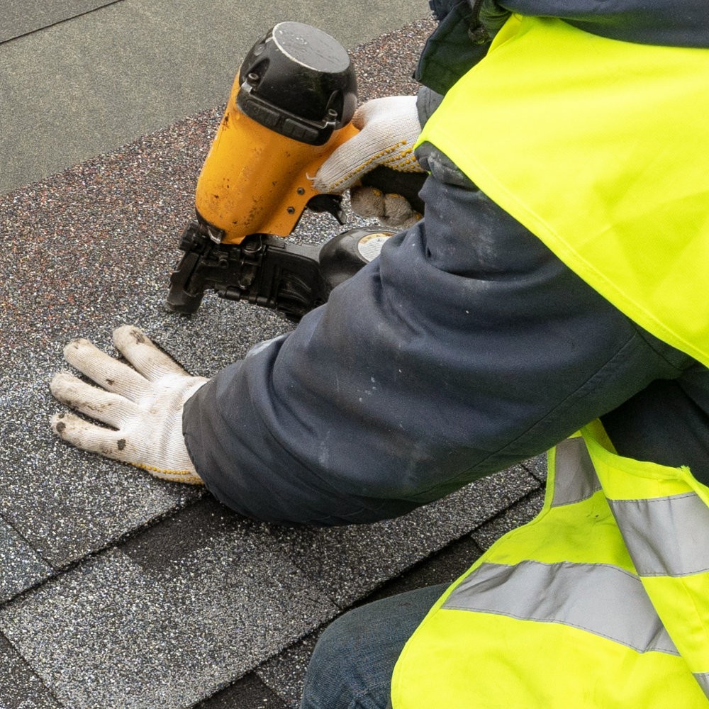 Worker replacing shingles on a roof